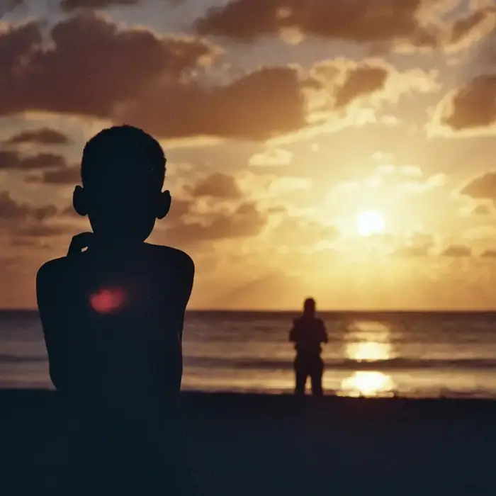 Silhouettes face au coucher du soleil sur la plage, île Maurice
